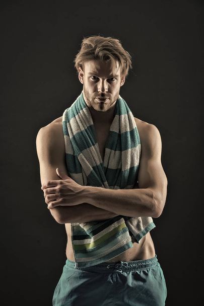 Man with towel on neck after training. Sexy sportsman with muscular chest and belly. Fitness athlete with fit torso in shorts. Sport and wellness. Hygiene, health and bodycare concept, vintage filter - Photo, image