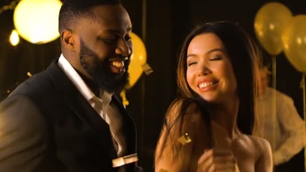 Lächelndes gemischtes Paar flirtet und tanzt unter fallendem Konfetti, Party - Filmmaterial, Video