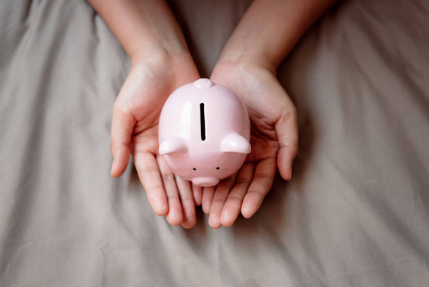 Close-Up of Woman Hands está sosteniendo Piggy Bank en el fondo de la tela, ahorrando dinero y Banca de Negocios o Concepto Financiero
.  - Foto, Imagen