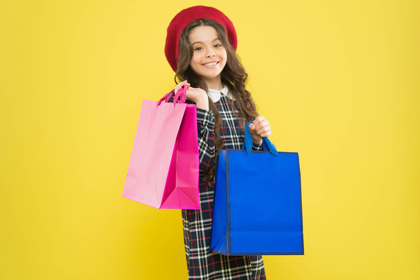 big sales. happy girl with long curly hair in beret. shopping. child with shopping bag. parisian child on yellow. little beauty shopaholic. Holiday present. little girl in hat. shopping sales - Foto, immagini
