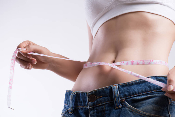 Lähikuva ohut nuori nainen mittaamalla hänen ohut vyötärö mittanauhalla. Terveydenhuolto ja nainen ruokavalio elämäntapa käsite vähentää vatsa ja muotoilla terve vatsa lihas
. - Valokuva, kuva