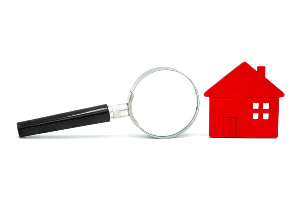 Red wooden houses and magnifying glass on a white isolated backg - Photo, Image