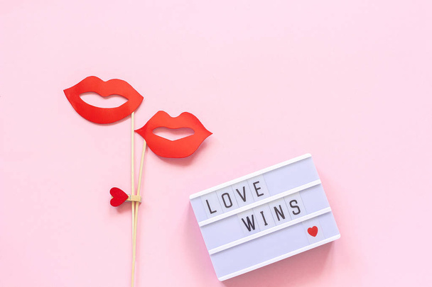 Lightbox with text Love wins and couple paper lips props on stick on pink background. Concept lesbian love National Day Against Homophobia Creative Valentine's Day Greeting card Top view - Фото, изображение