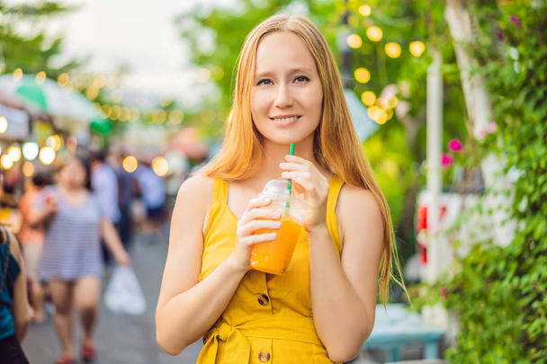 Женщина пьет апельсиновый сок на азиатском рынке
 - Фото, изображение