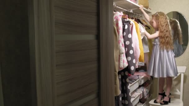 Красива маленька дівчинка вибирає плаття в домашньому гардеробі. Краса і мода
 - Кадри, відео