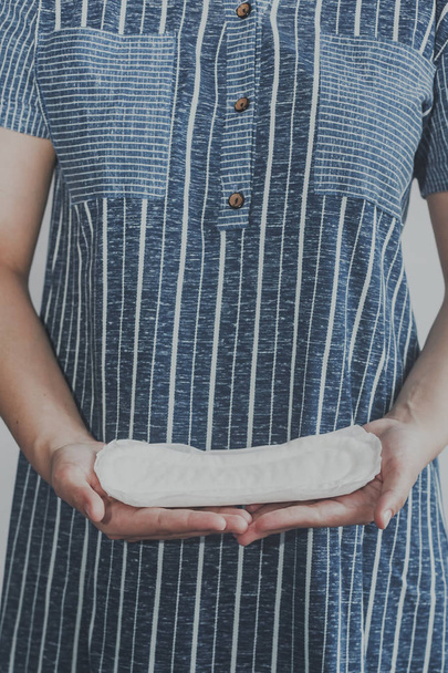 Young woman holding sanitary pads. Period days concept showing feminine menstrual cycle. - Photo, Image