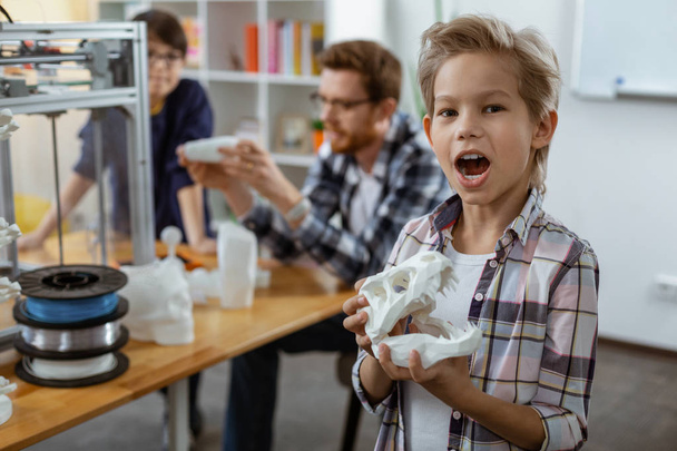 Excited little boy in checkered shirt playing with model of dinosaurs - Foto, immagini