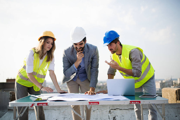Team of architects and engineer in group on construciton site check documents - Фото, зображення
