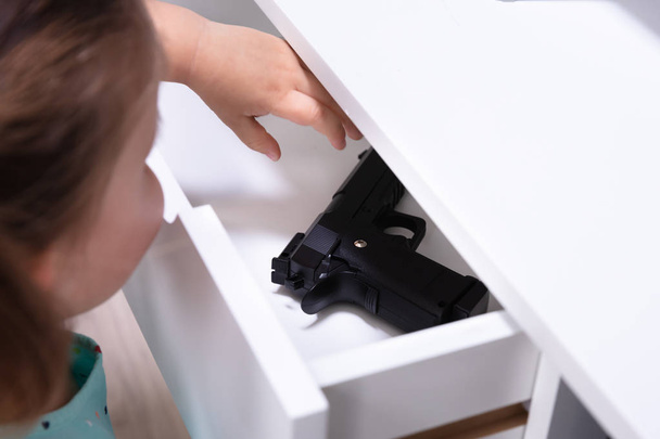 Close-up Girl Found Pistol In Drawer At Home - Foto, Imagem