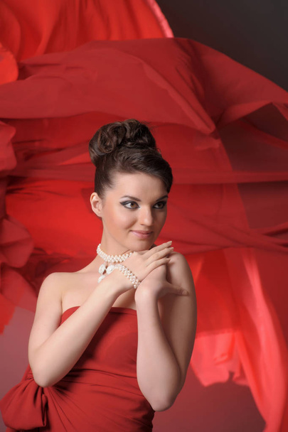 girl in a red dress  in the studio and flowing fabric - Photo, image