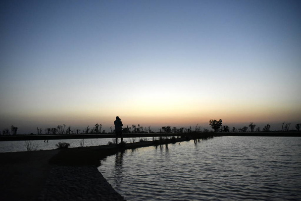 Silhouette Mann und Baby am See am Sonnenuntergang bei al qudra love l - Foto, Bild