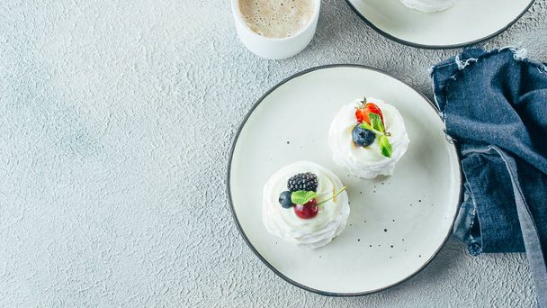 Десерт из безе Павлова со свежими ягодами на тарелке. Каменный фон. Копирование пространства, баннерное изображение, вид сверху
 - Фото, изображение