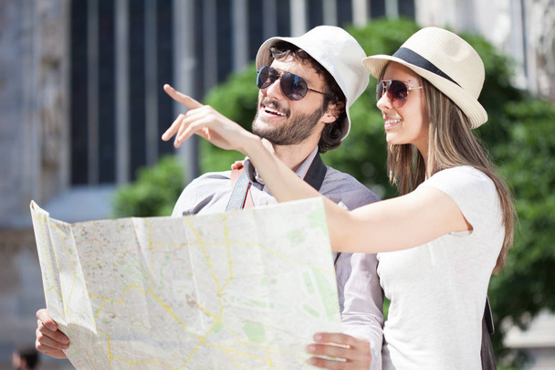 Happy couple of tourists holding a map - Photo, Image