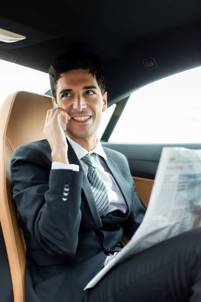 Manager on the phone sitting on the backseat of a car - Valokuva, kuva