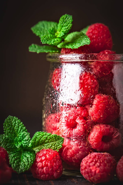 Raspberry. Raspberries and blueberries in a Cup on a dark background. Summer and healthy food concept. Background with copy space. Selective focus. - Foto, afbeelding