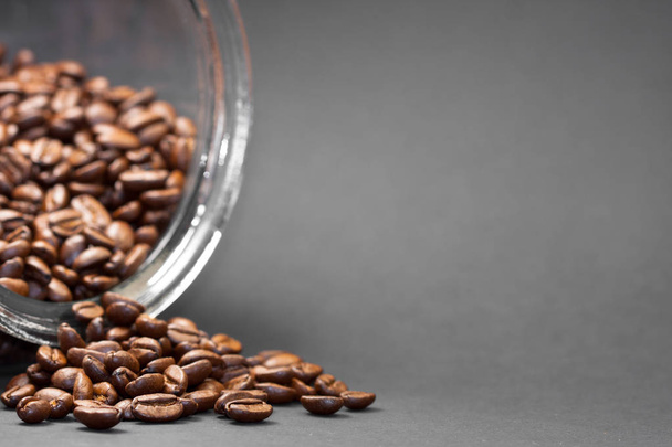 Fresh and ground roasted coffee beans from the coffee plant inside a cylindrical glass jar. - Photo, Image