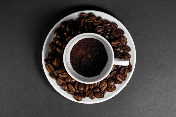 eine Tasse mit frisch gemahlenen gerösteten Kaffeebohnen mit Früchten aus der Kaffeepflanze mit einem Teller. - Foto, Bild