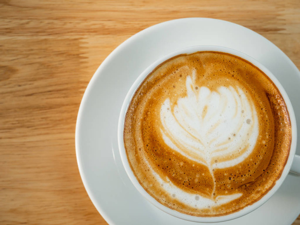 Закрыть латте-арт кофе на деревянном столе в кофейне
 - Фото, изображение