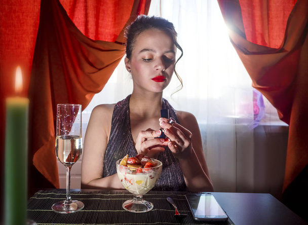 lipstick makeup using beautiful women in a restaurant. european woman with dark hair using red lipstick.Selective focus. - Fotó, kép