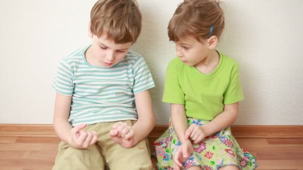 Boy and girl sit on floor leaning against wall - Materiaali, video