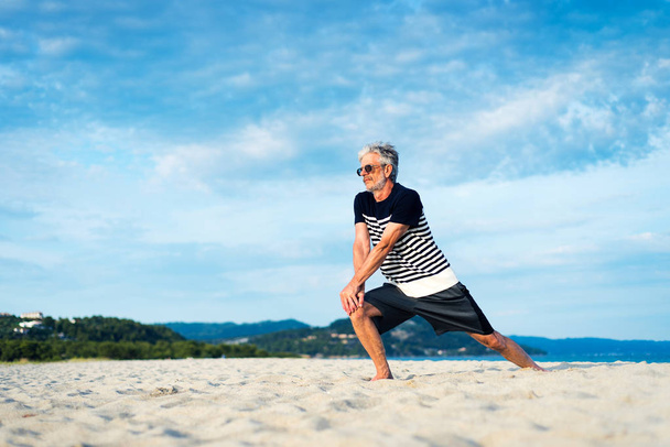 Senior man exercising on the beach - Valokuva, kuva