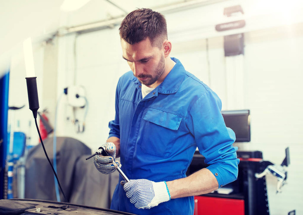 mechanic man with wrench repairing car at workshop - Foto, imagen