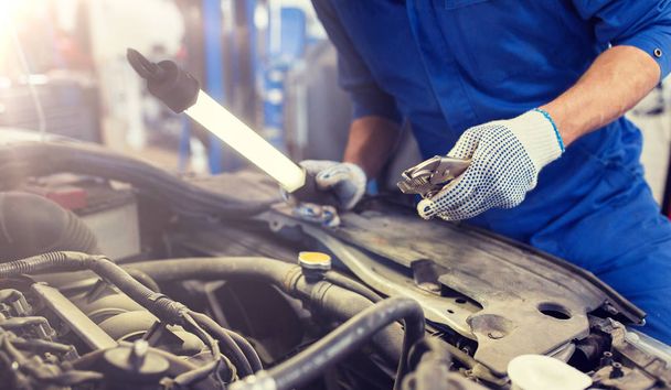 mechanic man with pliers repairing car at workshop - Zdjęcie, obraz