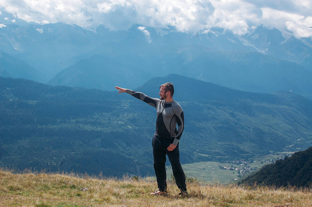 Muž ukazující směr s rukou stojící v horách ve sva - Fotografie, Obrázek