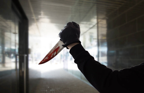 ręka w rękawiczce z krwią na nożu na ciemnym tunelu - Zdjęcie, obraz