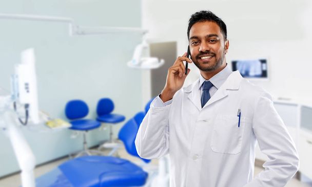 dentist calling on smartphone at dental clinic - Foto, immagini