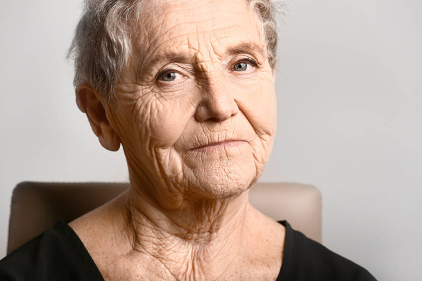 Portret van senior vrouw op grijze achtergrond - Foto, afbeelding