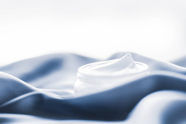 Crema facial de belleza en un frasco de seda azul suave
 - Foto, imagen