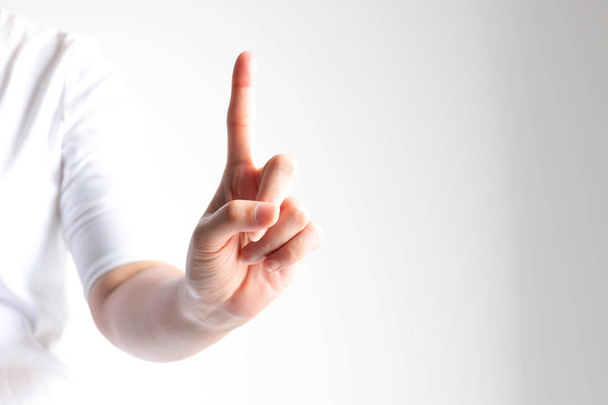 Рука, показывающая номер один, поднимая указательный палец крупным планом на белом фоне и мало света
. - Фото, изображение