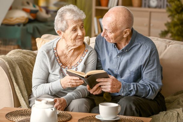 Retrato de pareja mayor leyendo libro en casa
 - Foto, Imagen