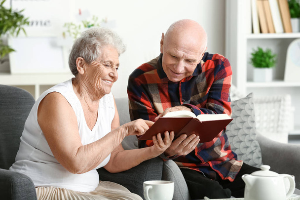 Portrait of senior couple reading book at home - 写真・画像