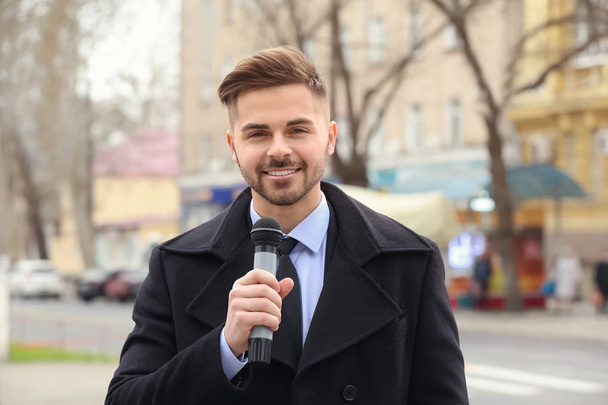 Reportero guapo con micrófono al aire libre
 - Foto, Imagen
