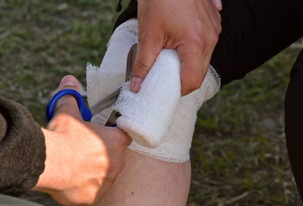 Um curativo e primeiros socorros estão sendo aplicados a um joelho ferido de um corredor
 - Foto, Imagem