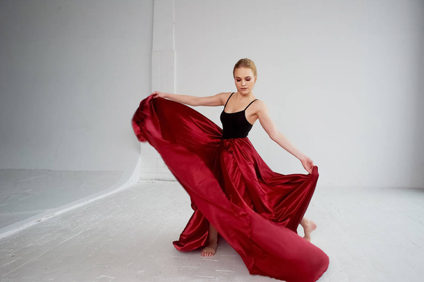 A gymnast in a dark top and a red silk skirt. The color of passion, of aggression.Tango. Plastic body, airiness , weightlessness and lightness. - Foto, Bild