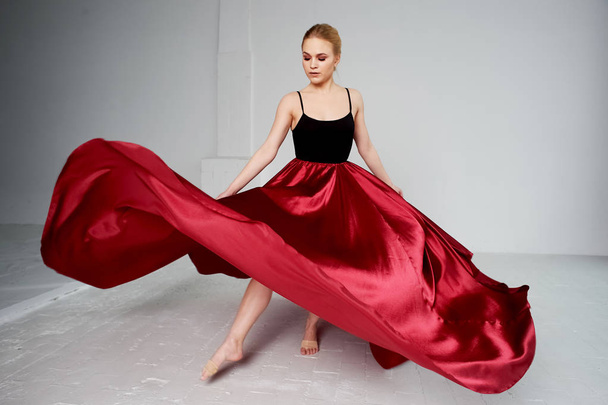 A gymnast in a dark top and a red silk skirt. The color of passion, of aggression.Tango. Plastic body, airiness , weightlessness and lightness. - Foto, afbeelding