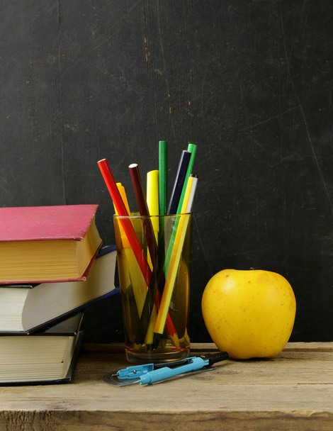Papelaria (caneta, lápis, régua, bússola) e um livro sobre fundo placa escola preta
 - Foto, Imagem