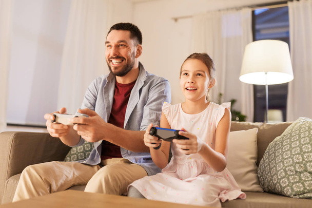 father and daughter playing video game at home - Фото, зображення