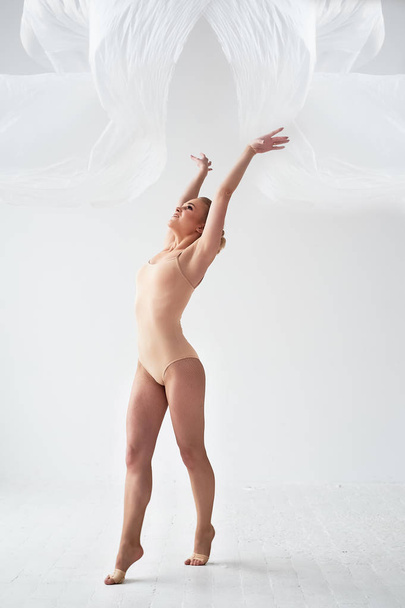 Gymnast dancing with a transparent film on a white wall and floor.Grace and healthy lifestyle. - Foto, Bild