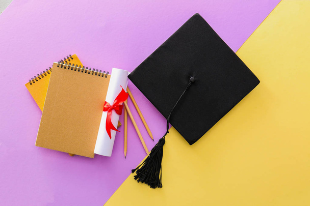 色の背景にモルタルボード、卒業証書と文房具。高校卒業の概念 - 写真・画像