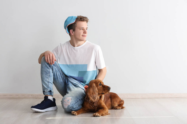 Ragazzo adolescente con simpatico cane vicino alla parete luminosa a casa
 - Foto, immagini