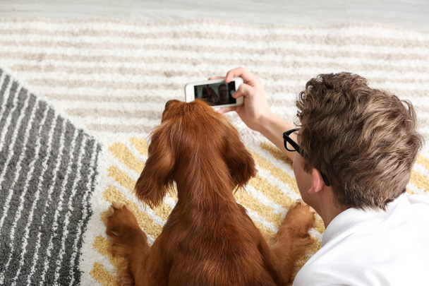 Έφηβος αγόρι με χαριτωμένο σκυλί παίρνει selfie στο σπίτι - Φωτογραφία, εικόνα