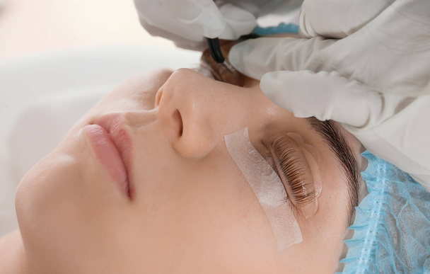 Young woman undergoing procedure of eyelashes lamination in beauty salon, closeup - Foto, Bild