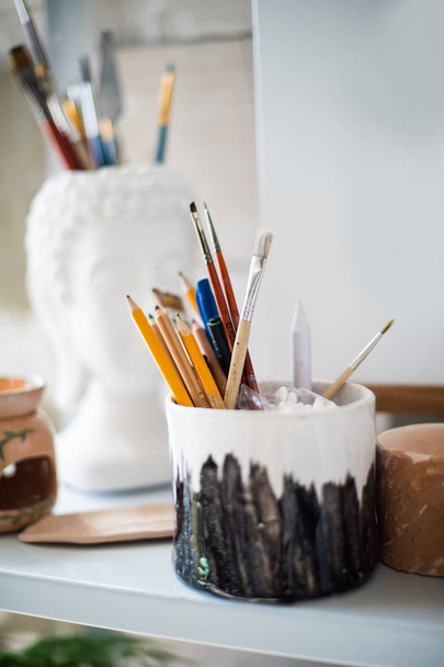 Pencils and brushes on shelf in artistic studio - Photo, Image