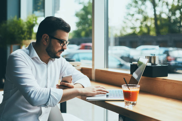 молодой привлекательный бизнесмен в очках работает в кафе
 - Фото, изображение