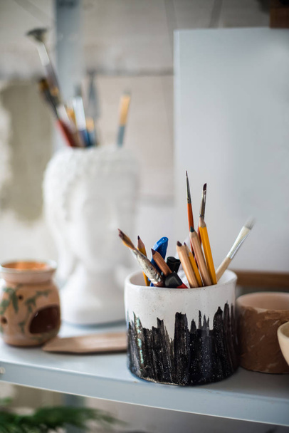 Lápices y pinceles en estantería en estudio artístico
 - Foto, imagen