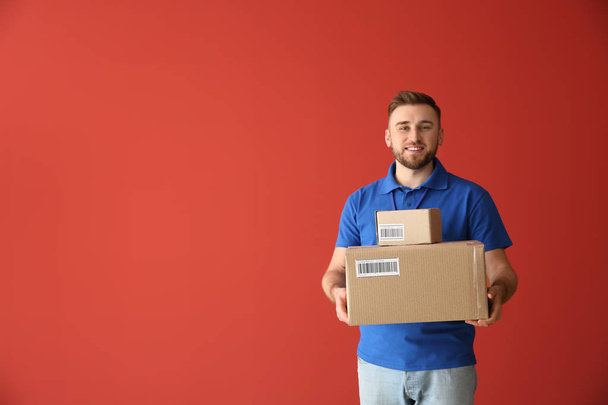 Handsome delivery man with boxes on color background - Photo, Image